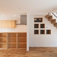 居間と台所の間には目隠しの意味を持つ収納棚を設け階段の壁の向こう側には家事スペースが並ぶの画像